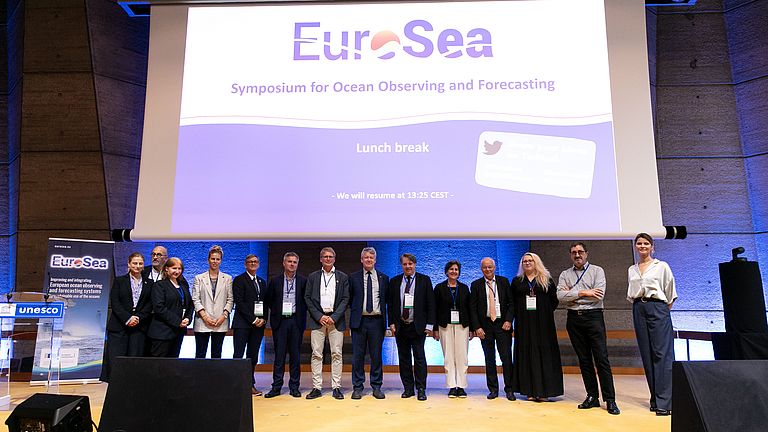 A group of people on a stage. A screen can be seen in the background. Inscription: EuroSea.