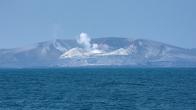 [Translate to English:] Ein rauchender eingestürzter Vulkankegel im Meer