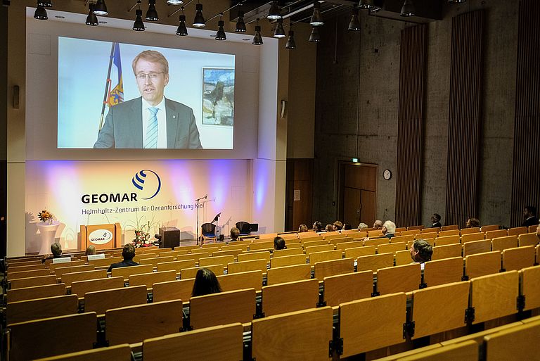 View of the lecture hall with a video message by Minister President Daniel Günther
