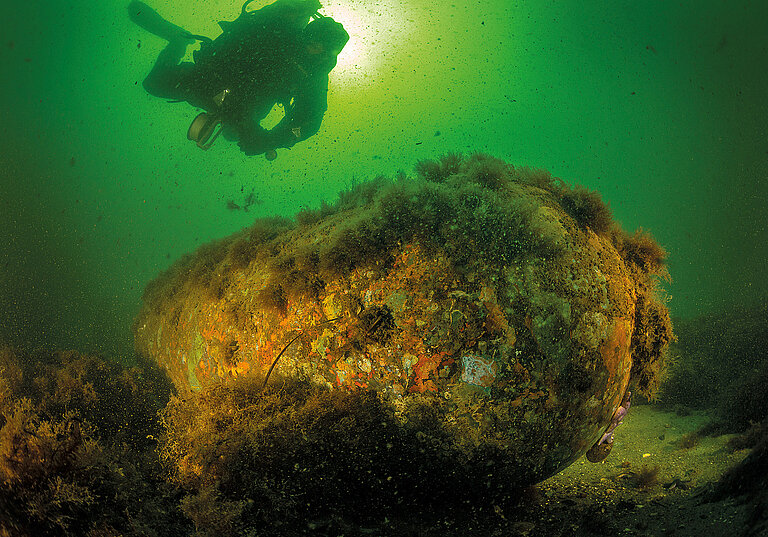 A research diver examines a sea mine