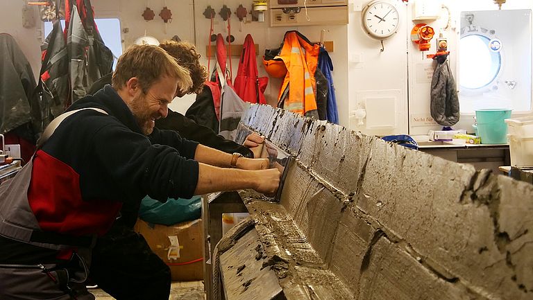 Johann Philipp Klages and Thomas Arney sample a sediment core that was extracted from the sea floor using a box corer. Photo: Marlena Witte, Alfred Wegener Institute