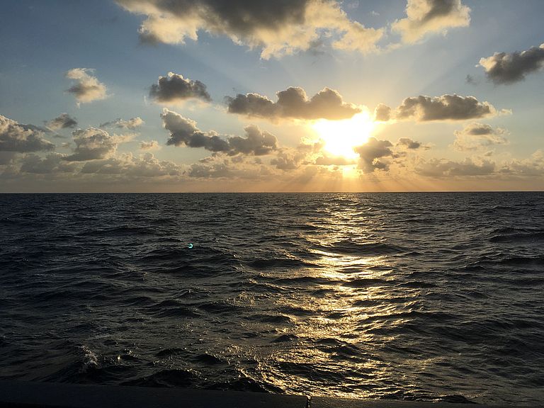 Sunlight and clouds above an ocean surface.