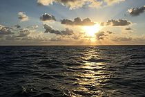 Ocean surface with clouds and sunlight.