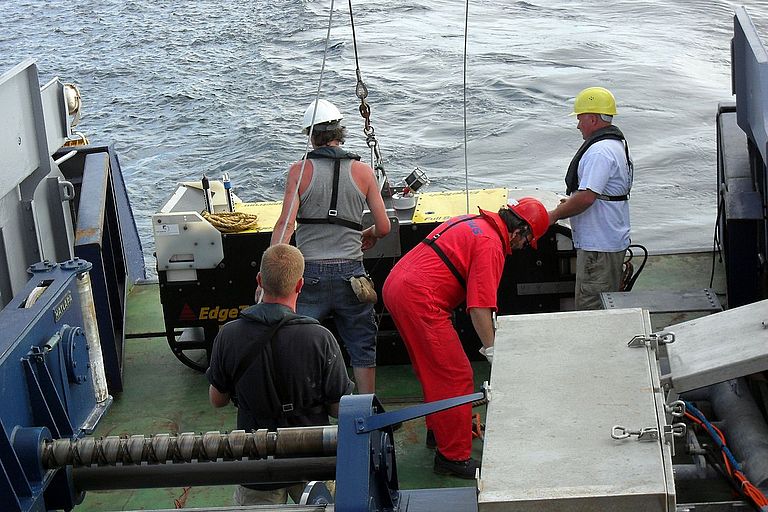 Wissenschaftler und Besatzungsmitglieder bereiten an Bord des Forschungsschiffes POSEIDON ein SeitenSidescan-Sonar zum Einsatz vor. Das Gerät wird anschließend hinter dem Schiff geschleppt, sendet akustische Signale in Richtung Meeresboden und empfängt die vom Meeresboden zurück kommenden Signale. Daraus können präzise Karten des Meeresbodens erstellt werden. Foto: Inga Golbeck