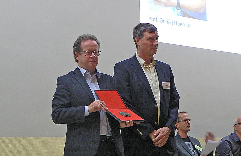 Dr. Heinz-Gerd Röhling, Schatzmeister der Deutsche Geologische Gesellschaft – Geologische Vereinigung (DGGV) bei der Überreichung der Gustav-Steinmann Medaille an Prof. Dr. Kaj Hoernle. Foto: DGGV