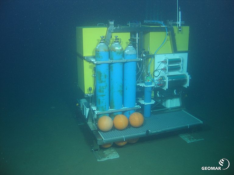 Das Bild zeigt den Aufbau des Gasfreisetzungsexperimentes mit dem Ocean Elevator Lander (mit gelbem Auftriebsschaum) und angebauten Geräten (CO2 und Krypton Gasflaschen, Batteriegehäusen, Steuereinheit und Gasauslass) verankert in ca. 80 Meter Wassertiefe in der Nähe des CO2-Speicherkomplexes Sleipner. Foto: ROV-Team/GEOMAR