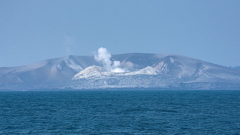 Ein rauchender eingestürzter Vulkankegel im Meer