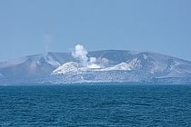 Ein rauchender eingestürzter Vulkankegel im Meer