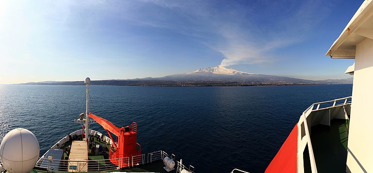 Expedition aboard the research vessel METEOR in the Strait of Messina off Sicily to study submarine natural hazards in the Mediterranean. A volcanic eruption of Mount Etna can be seen in the background. Photo: Julio Beier, Future Ocean