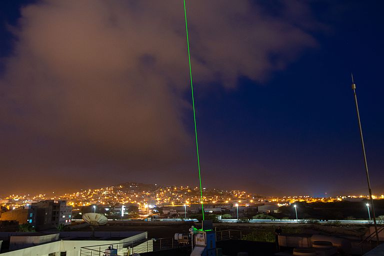 A green laser goes from the OSCM vertically into the night sky over Mindelo.