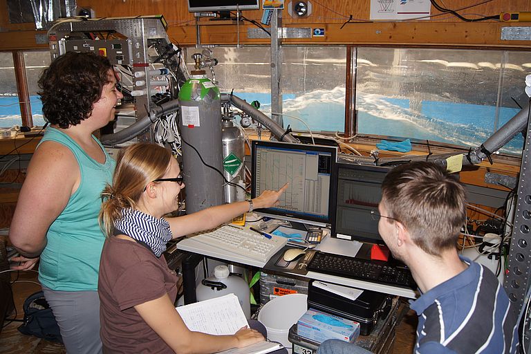 Mit Blick auf die winderzeugten Wellen am Aeolotron diskutieren (von links nach rechts) Dr. Mariana Ribas Ribas (Universität Oldenburg), Dr. Anke Nölscher (Max-Planck-Institut für Chemie, Mainz) und Jakob Kunz (Universität Heidelberg). Foto: Kerstin Krall, Institut für Umweltphysik, Universität Heidelberg