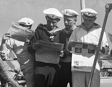 Seamen reading newspaper