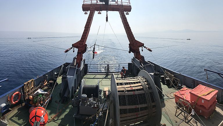 The stern of a ship, behind it measuring cables on the water