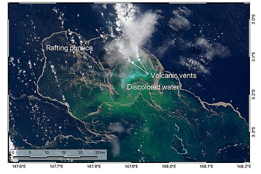 Satellitenaufnahme der Meeresoberfläche, das Wasser ist dunkelblau aber stellenweise grün verfärbt, eine weiße Dampfwolke steigt aus dem Wasser auf