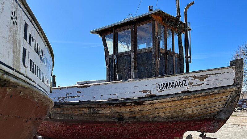 Two fishing boats on the shore, with paint peeling off their hulls