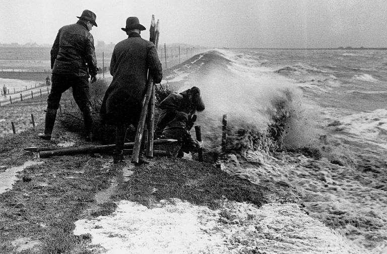 In der Regel lassen sich während einer Sturmflut im Kronenbereich keine Deichsicherungsarbeiten ausführen. Die Aufnahme zeigt eine Sturmflut in der ersten Hälfte des 20. Jahrhunderts. Es ist auch in dem neuen Buch von Robert Stadelmann: Den Fluten Grenzen setzen, Schleswig-Holsteins Küstenschutz Westküste und Elbe, Band 1: Nordfriesland, zu sehen. (Foto: Archiv ALR bzw. LKN Husum)
