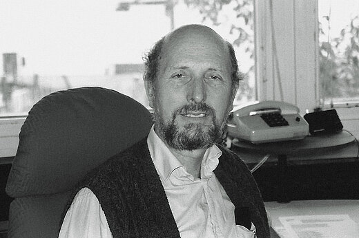 Portrait of an older man with a receding hairline at his desk in the office