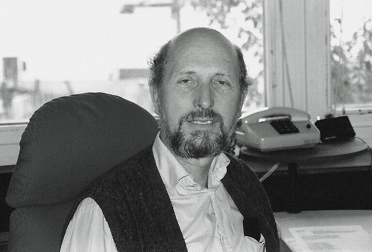 Portrait of an older man with a receding hairline at his desk in the office