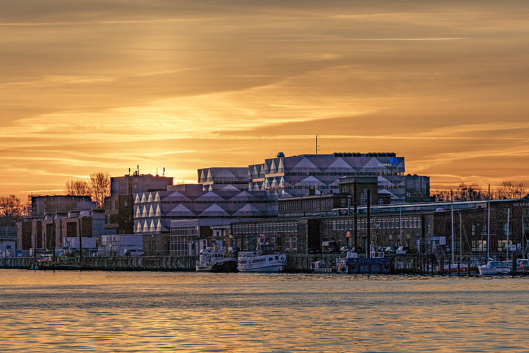 Gebäude an einem Fluss in goldenem Morgenlicht