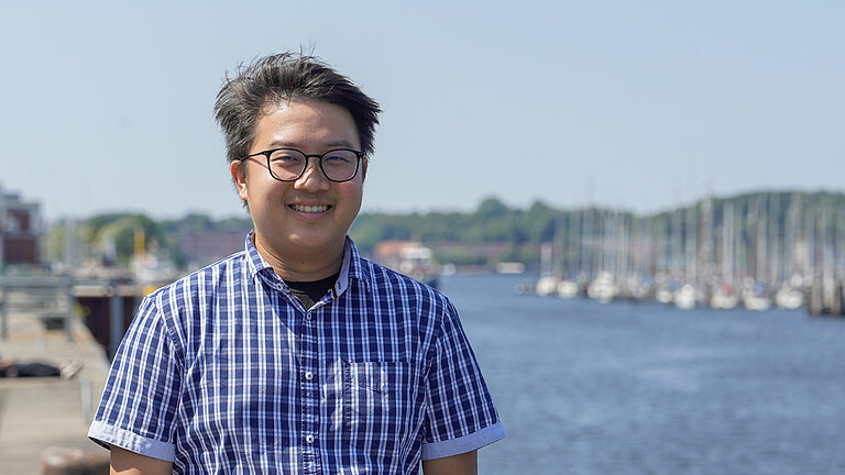 A photo of Jeng Hann Chong standing in front of a body of water.