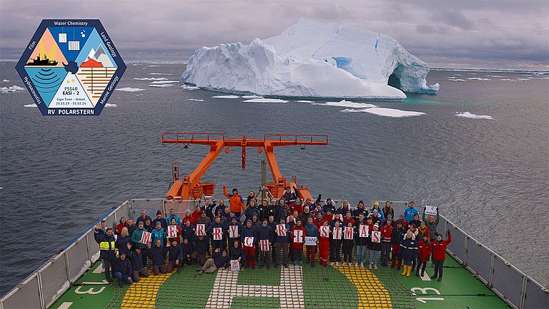 Die Besatzung eines Forschungsschiffes hält Buchstaben hoch, auf denen "Merry Christmas" zu lesen ist