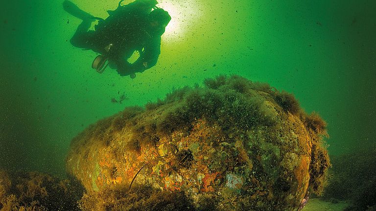 Ein Forschungstaucher untersucht eine Seemine aus dem Zweiten Weltkrieg 