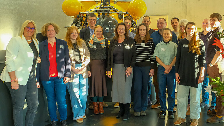 Eine Gruppe Menschen in einem Foyer, im Hintergrund ein ausgestelltes gelbes Tauchboot