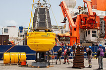 Eine riesige Boje steht im Hafen vor einem Forschungsschiff