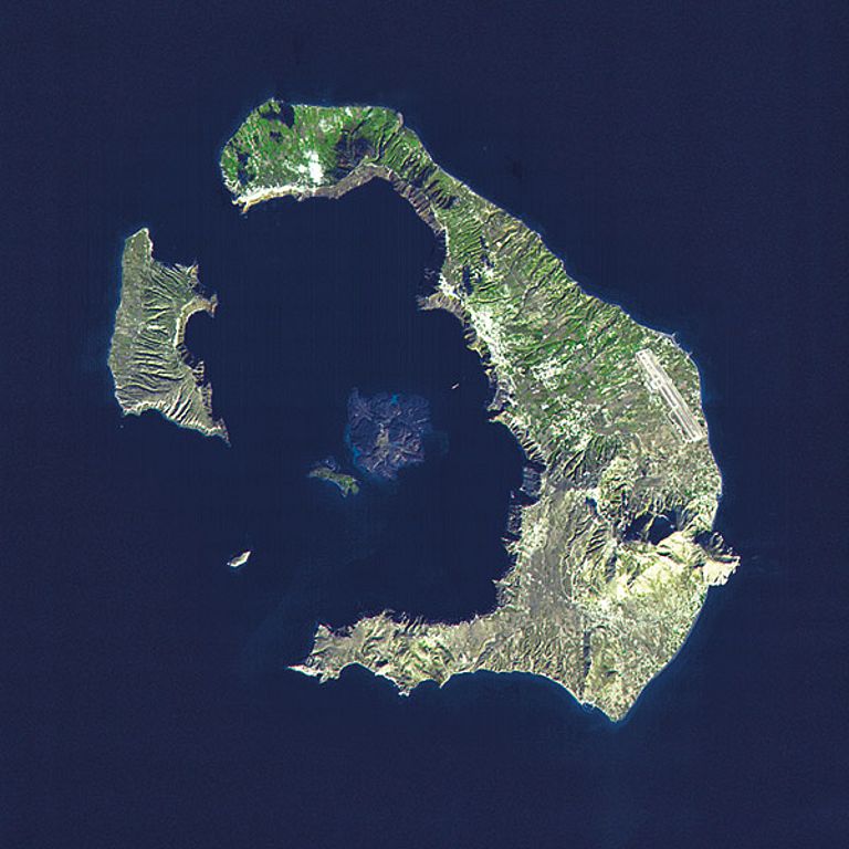 Die Inselgruppe Santorin von oben. Die ringförmig angeordneten Inseln Thira, Thirasia und Aspronisi bilden den Rand einer vom Meer gefluteten Caldera, in deren Mitte schon ein neuer Vulkan heranwächst (die Inseln Palea Kameni und Nea Kameni). Satellitenfoto: NASA