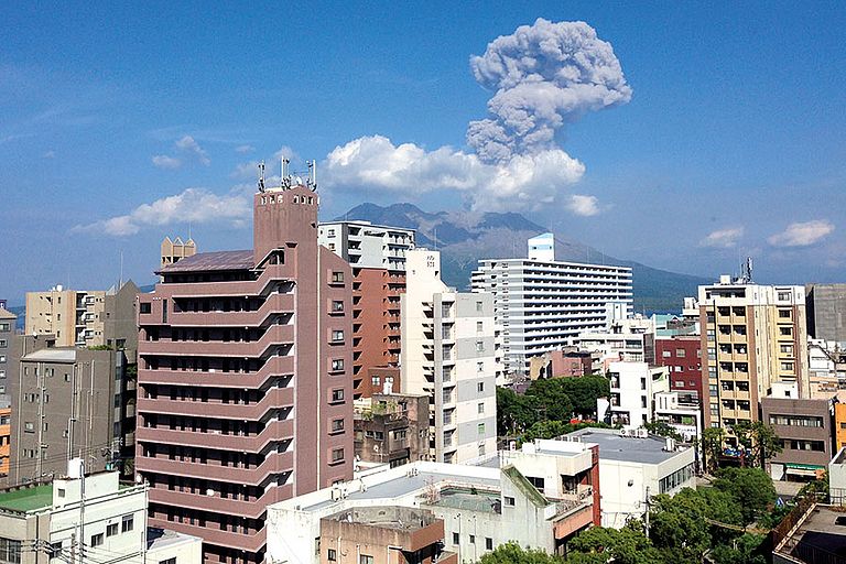 Blick auf den rauchenden Sakurajima mit der Skyline der japanischen Stadt Kagoshima. Die Aschewolken des Vulkans sind eine stete Gefahr für die Stadt und ihre Bewohner. Foto: Kaj Hoernle / GEOMAR