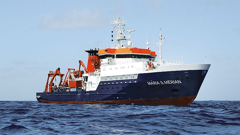 A research vessel with a dark blue hull and white superstructure at sea