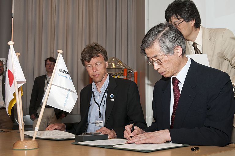 Professor Katsuaki Shimazu, Dekan der Faculty of Environmental Earth Science der Universität Hokkaido (vorne) unterzeichnet das Kooperationsabkommen. Hinten: Professor Martin Visbeck, Leiter der Physikalischen Ozeanographie am GEOMAR und Sprecher des Kieler Exzellenzclusters "Ozean der Zukunft" in Vertretung von GEOMAR-Direktor Professor Peter Herzig. Foto: J. Steffen, GEOMAR