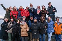 Eine Gruppe Jugendlicher steht auf der Promenade und winkt fröhlich.