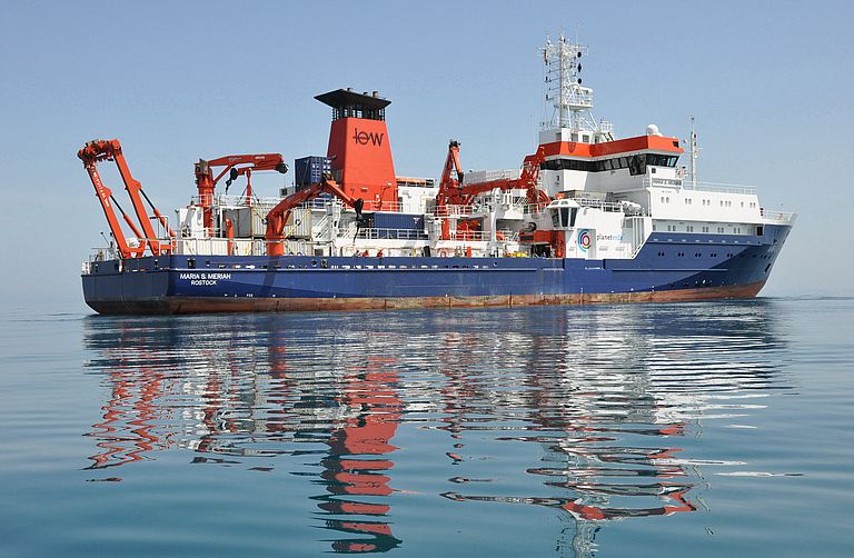 Das blau-weiß-rote Forschungsschiff MARIA S. MERIAN von der Seite auf See.