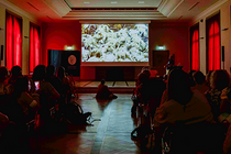 Ein Kinossal mit roten Wänden. Auf der Leinwand ist ein Tiefseemotiv zu sehen