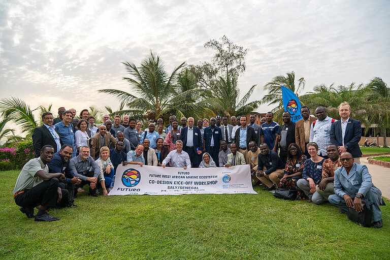 People gather for a group photo, holding a banner in their hands.