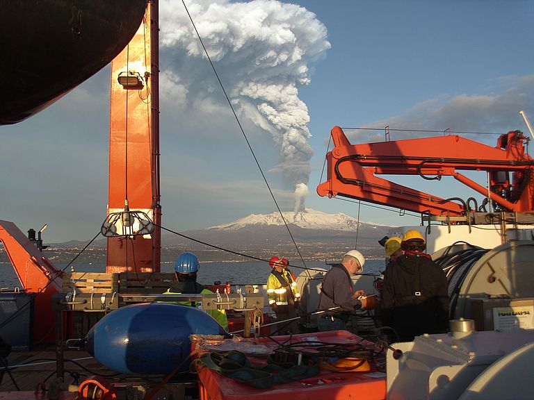 Deployment of 3D seismic instruments from the research vessel METEOR off Sicily. A volcanic eruption of Mount Etna can be seen in the background. Photo: Sebastian Krastel, Future Ocean