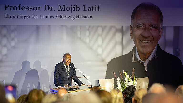 Ein älterer Mann im Anzug spricht an einem Rednerpult.