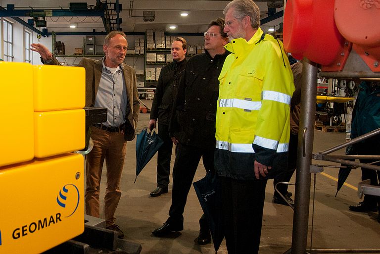 Dr. Peter Linke (l), Leiter des Technik- und Logistikzentrums erläutert Wirtschaftsminister Reinhard Meyer (2.v.r.) und GEOMAR Direktor Prof. Dr. Peter Herzig (r.) innovative Tiefseetechnologien. Foto: Jan Steffen, GEOMAR.