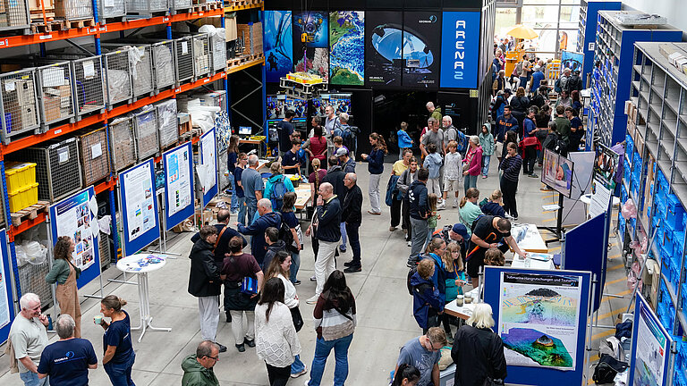 A hall with information stands and lots of visitors