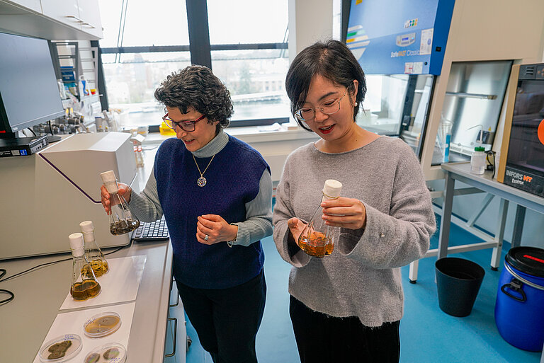 Zwei Frauen mit glatten dunklen Haaren arbeiten in einem modernen Labor