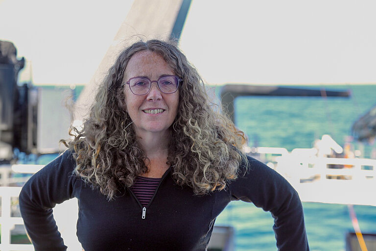 Porträt einer Frau mit langen welligen Haaren an Bord eines Forschungsschiffes