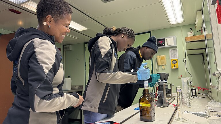 Young people of colour are happily working together in a laboratory on a research vessel